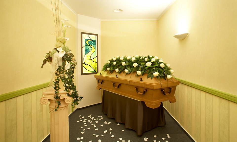Abschiedsraum mit aufgebahrtem Sarg und Blumendekoration bei Voss Bestattungen in Paderborn